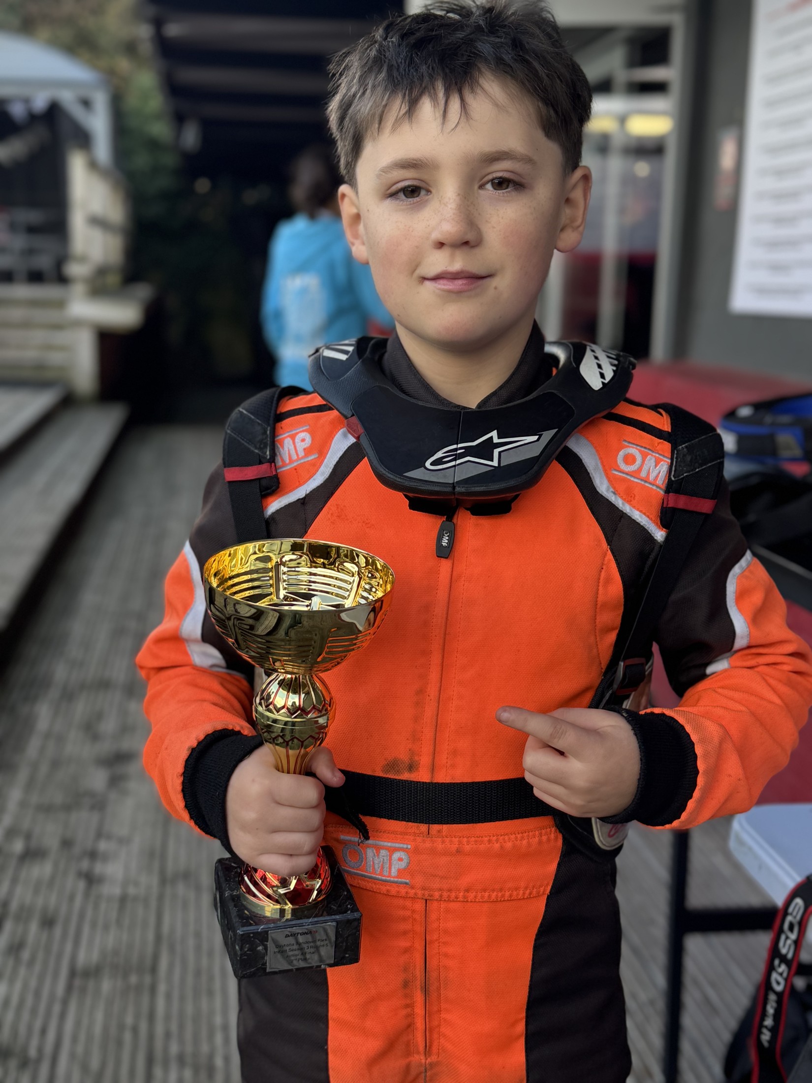 Felix in an orange race suit holding a trophy