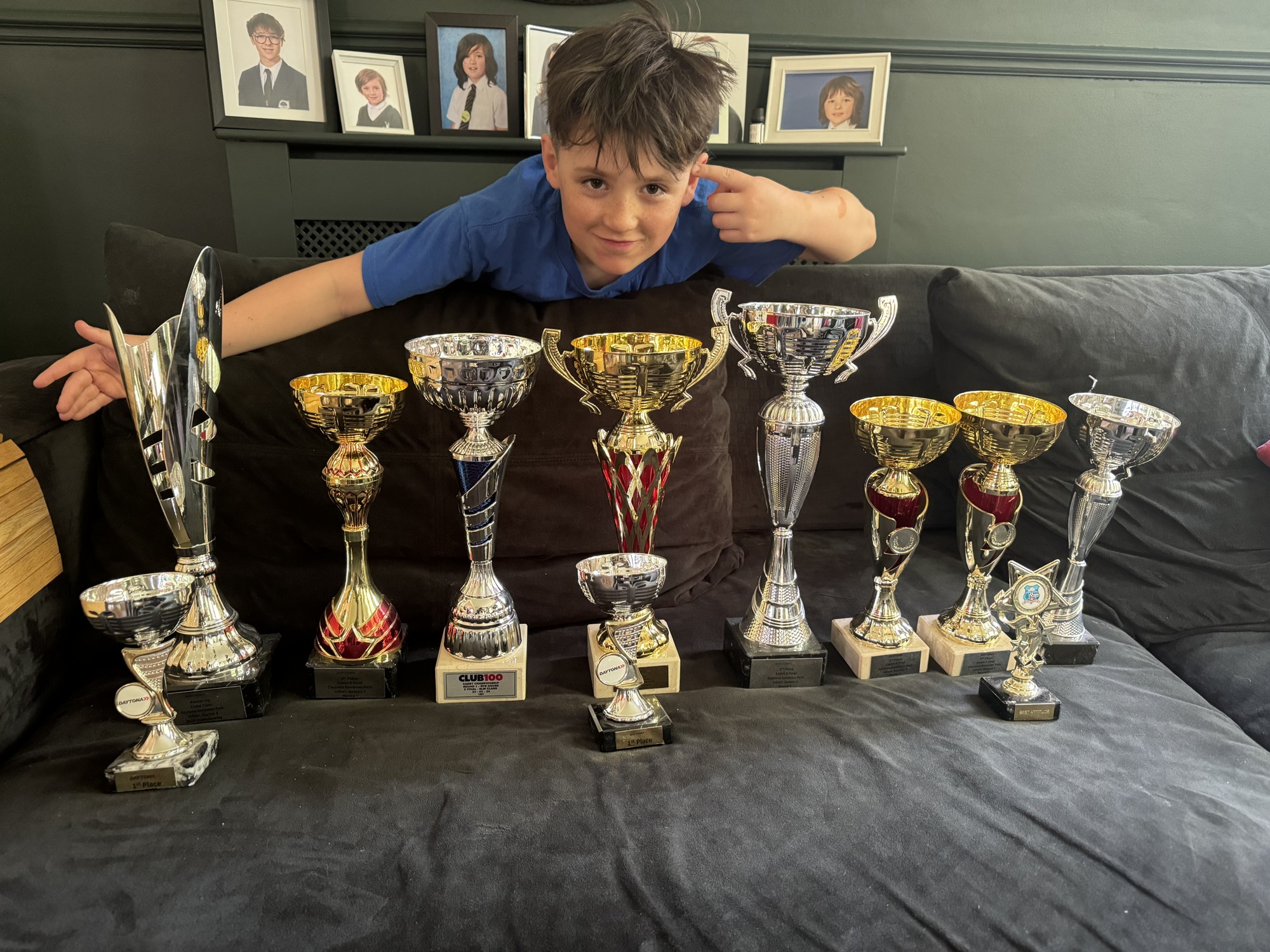 Felix smiling behind a collection of his racing trophies